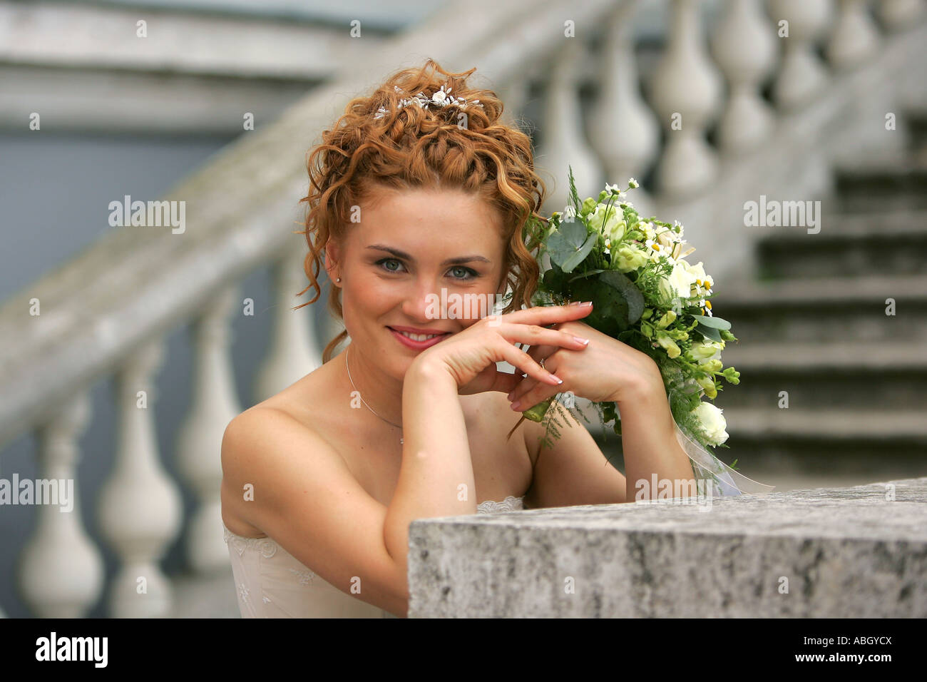 A portrait of a bride in a traditional white wedding dress pictured on her wedding day. She is stood in a half body portrait hol Stock Photo