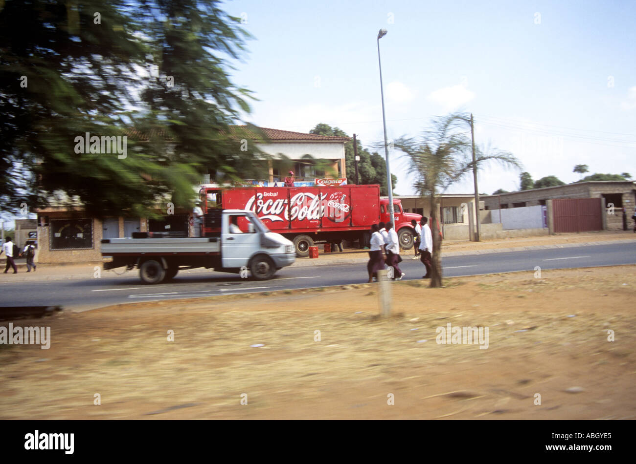 Boys running next to a Coca Cola or Coke truck or lorry outside Maputo Mozambique Stock Photo