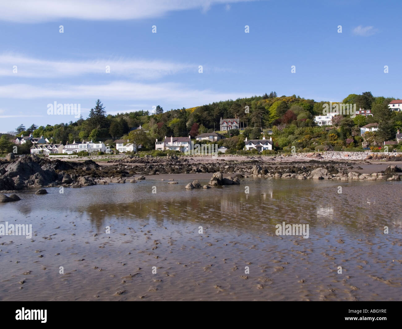 Village seafront houses from across rippled wet sand on empty beach at