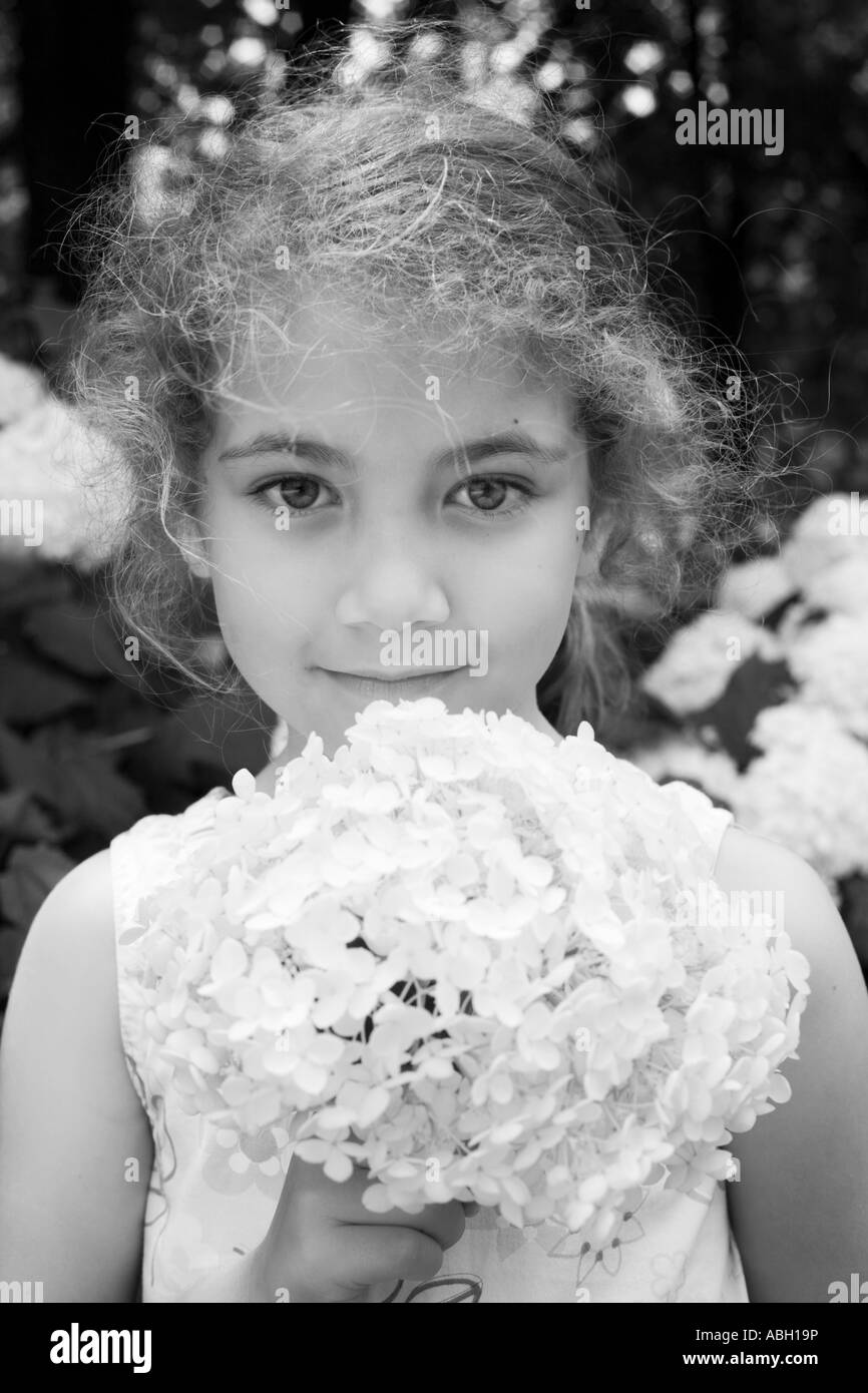 Young girl holding an hydrangea flower and looking at camera Stock Photo