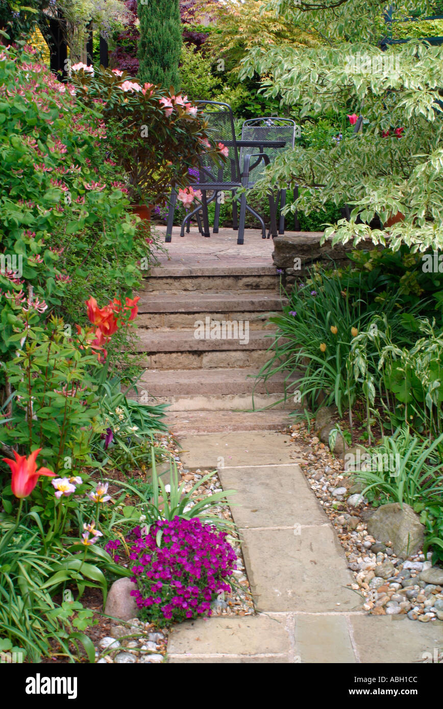 A slabbed path to a hidden patio with table and chairs Stock Photo Alamy