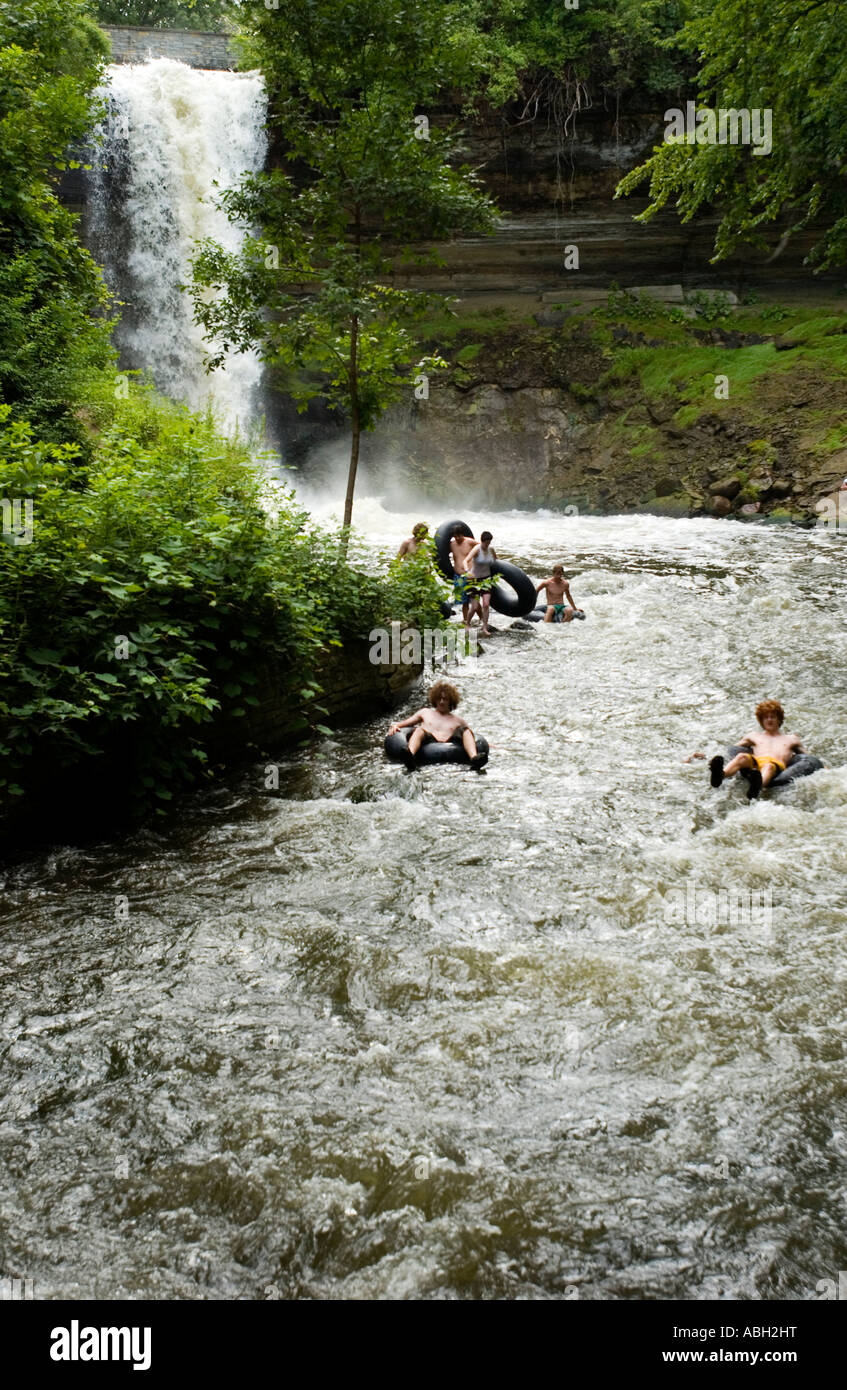 People innertubing down a river with a waterfall in the background