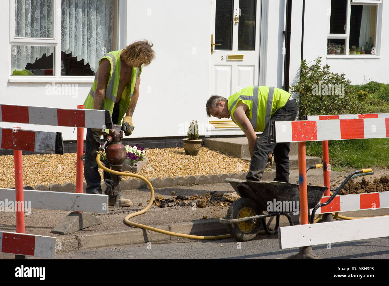 road workers digging a trench to install utility cables in UK Stock Photo