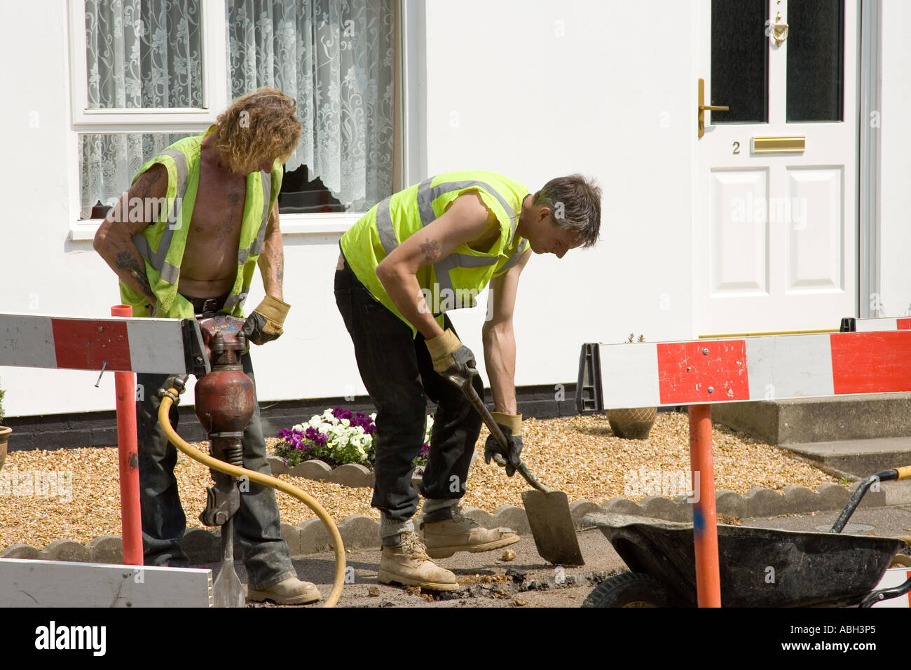 road workers digging a trench to install cables in Stow Road in Ixworth, Suffolk, UK Stock Photo