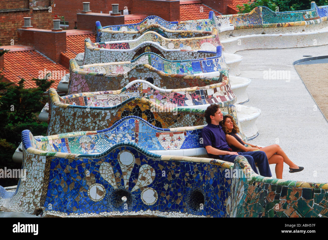 Couple on mosaic tile bench by Antonio Gaudi at Guell Park in Barcelona Spain Stock Photo