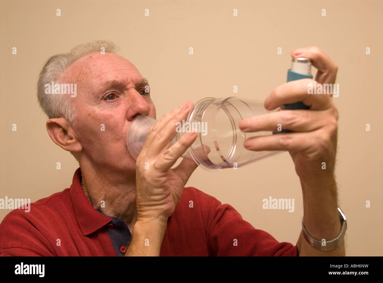 71 year old elderly man with asthma using a paediatric volumatic spacer and ventolin to alleviate symptons London UK Stock Photo