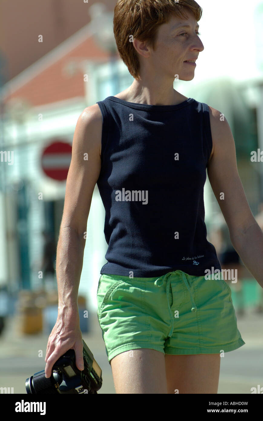 Caucasain woman holding a SLR camera and walking Stock Photo