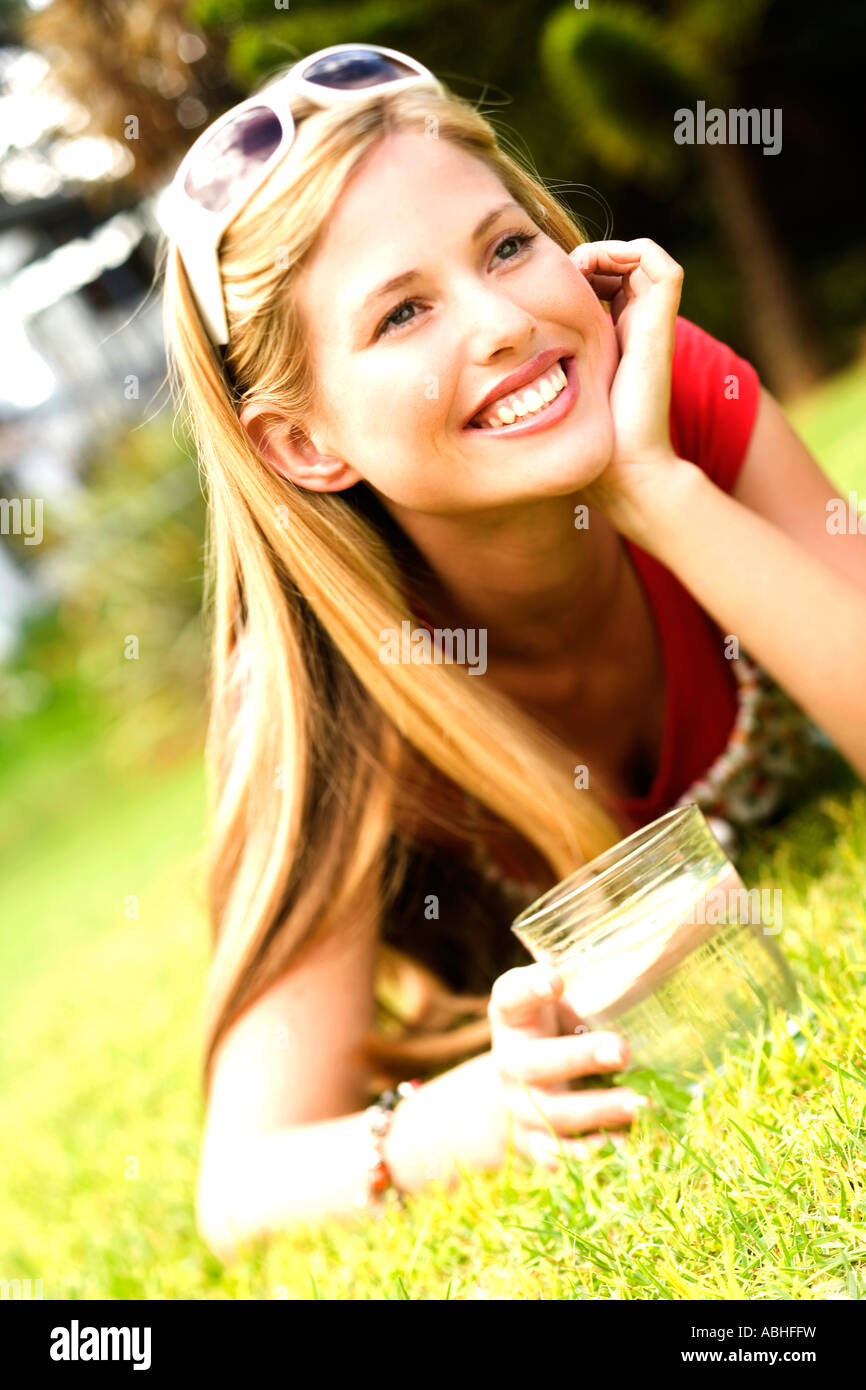Young smiling woman lying on grass, glass of water Stock Photo - Alamy