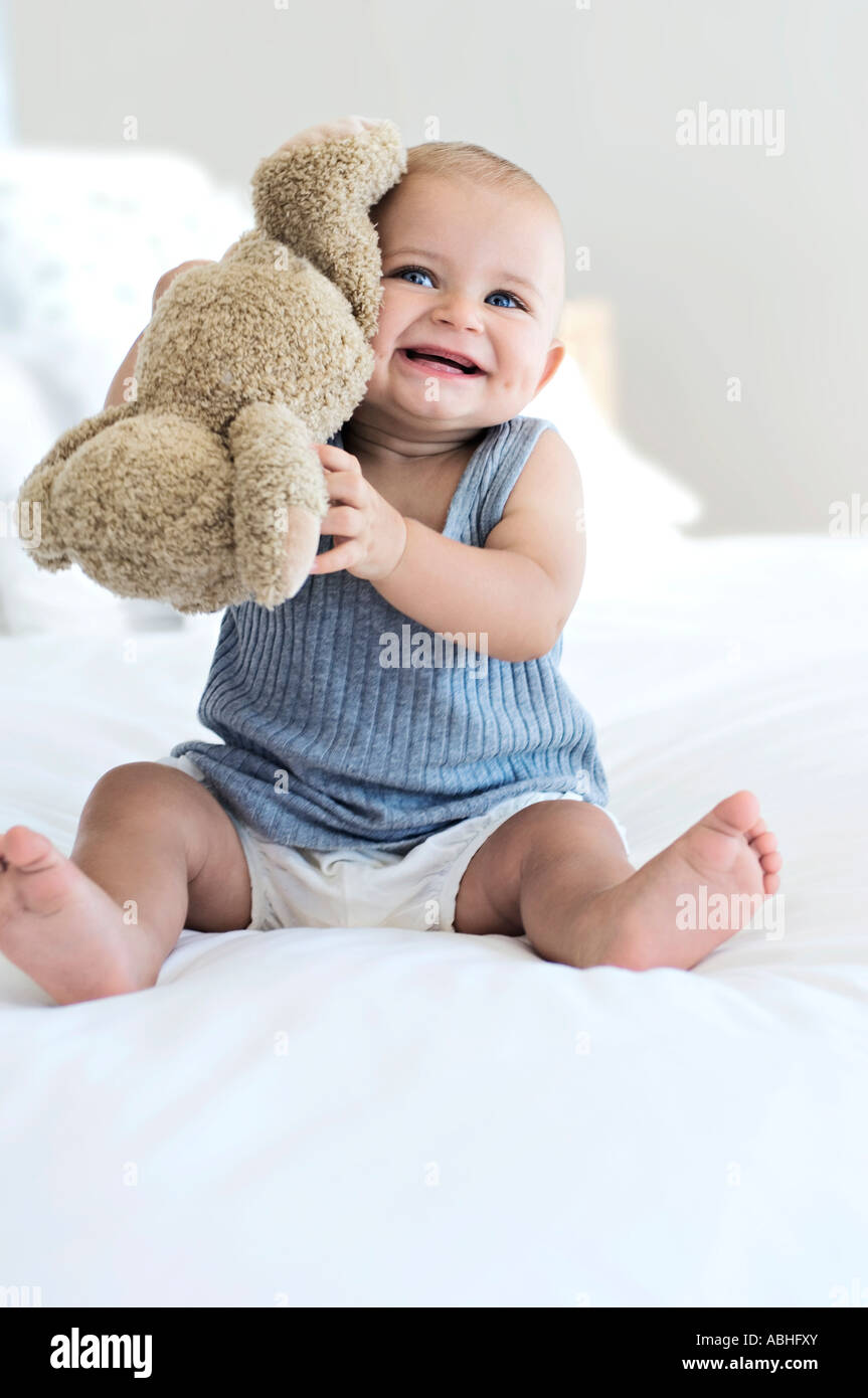 Baby sitting with teddy bear, indoors Stock Photo - Alamy