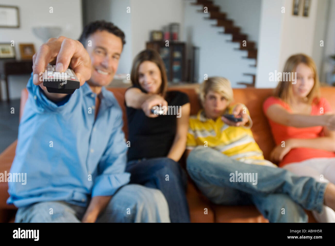 Parents and two teens holding eachothers a remote control, indoors