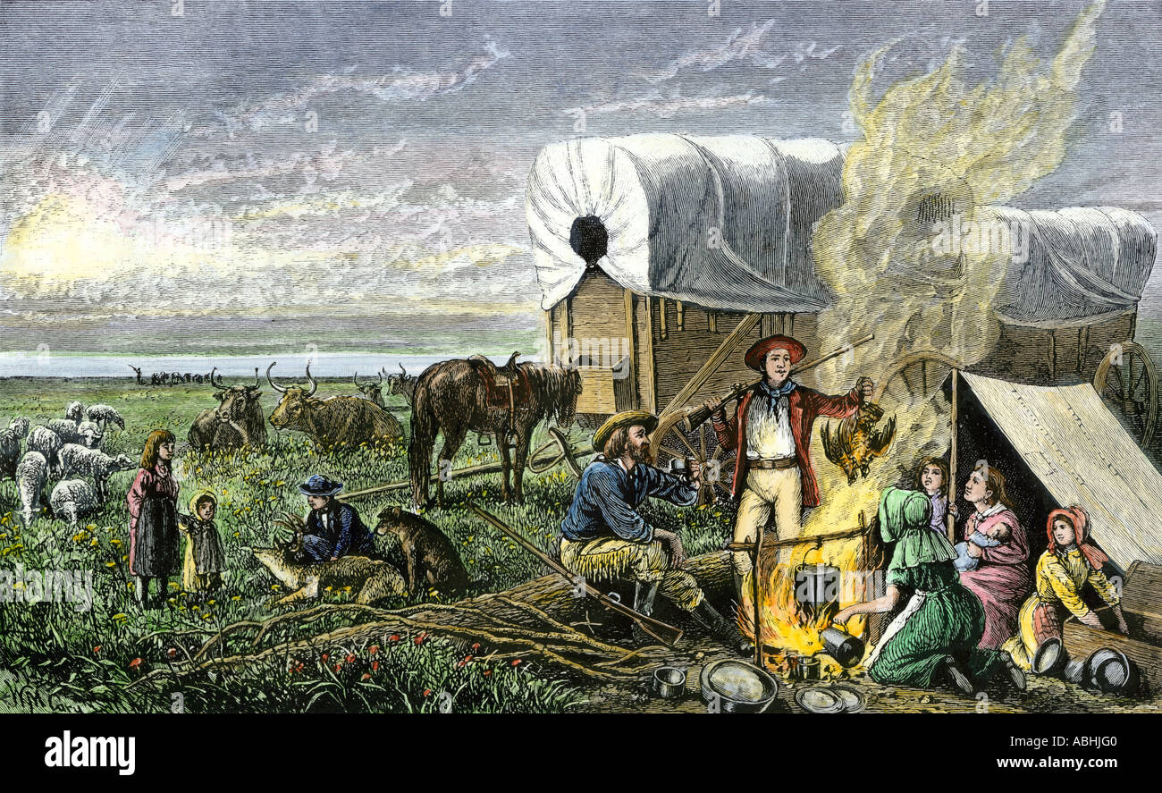 Pioneer family camped beside their covered wagons on a trail west 1800s. Hand-colored woodcut Stock Photo