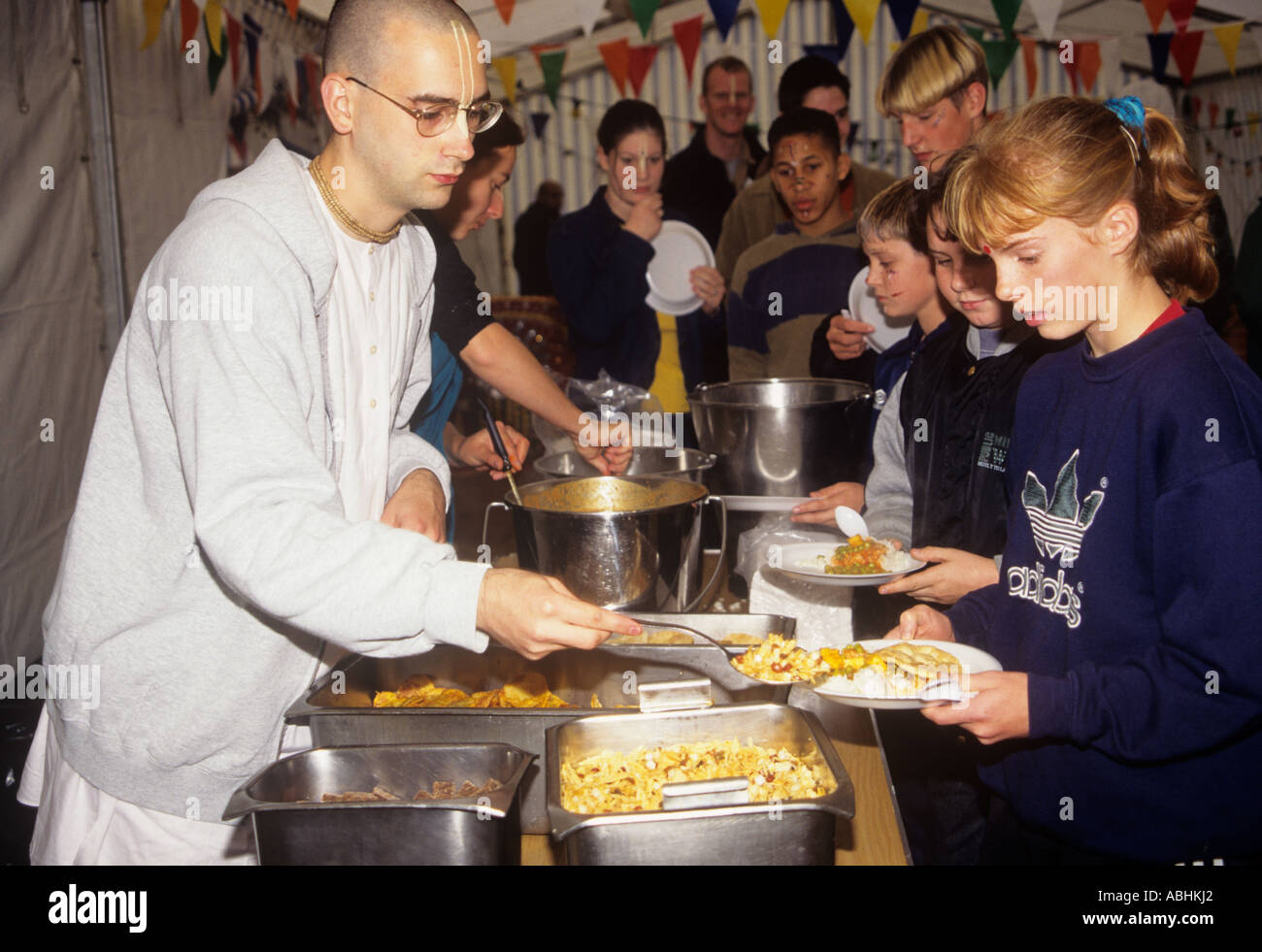 Members of the Hare Krishna temple committee at Watford serve a free meal for school visitors, England Stock Photo