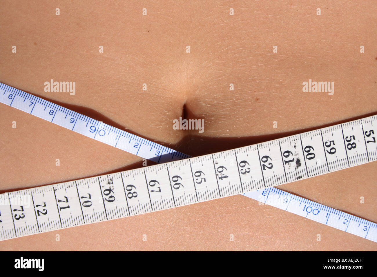 belly of a young woman measuring waist. Measuring tape INCH and CM