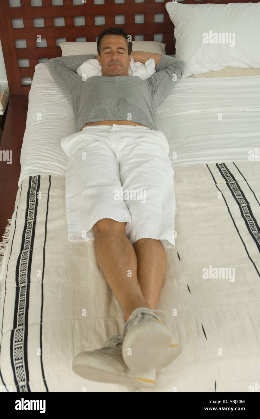 Man lying on a bed, indoors Stock Photo