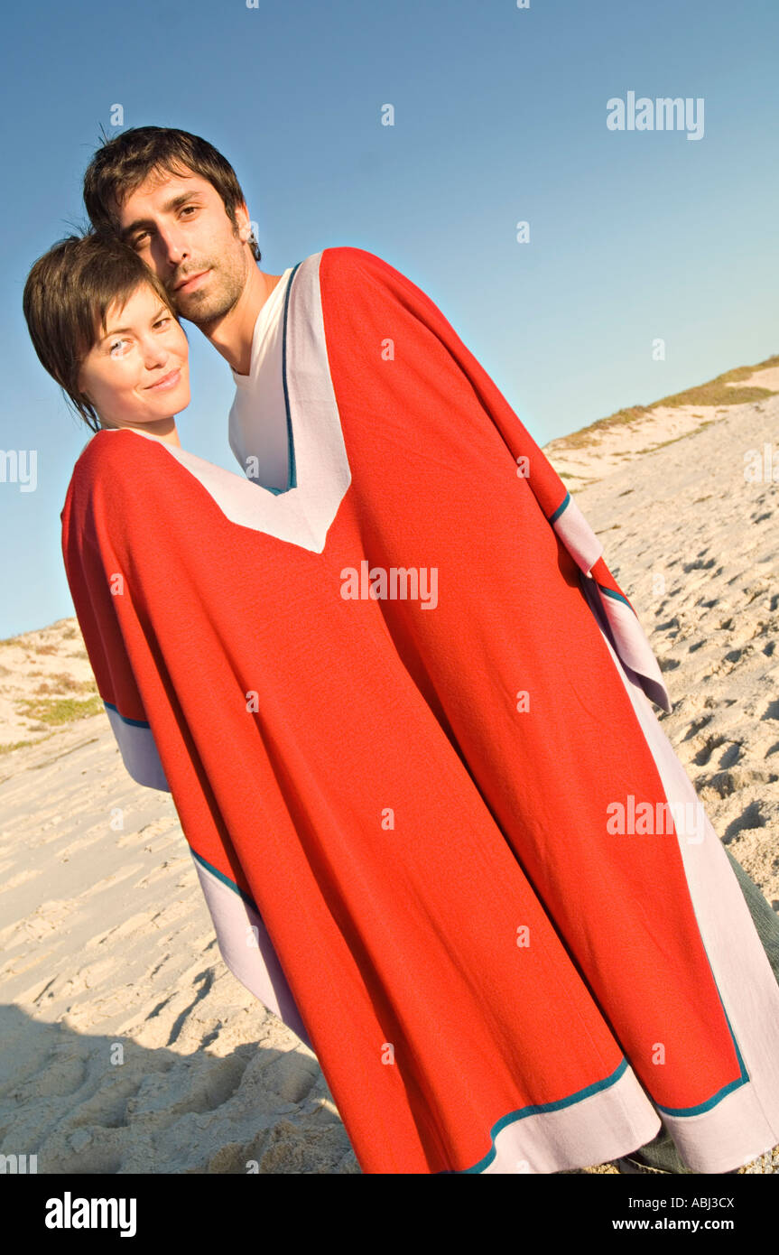 Dear Same anywhere Couple on the beach, sharing a poncho Stock Photo - Alamy