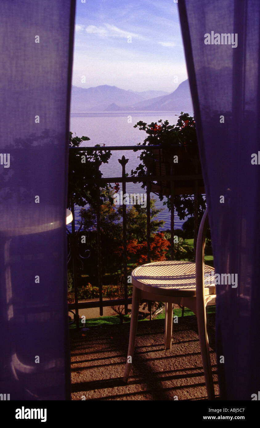 Room with a view of Italian Lakes with chair on balcony and curtains Stock Photo