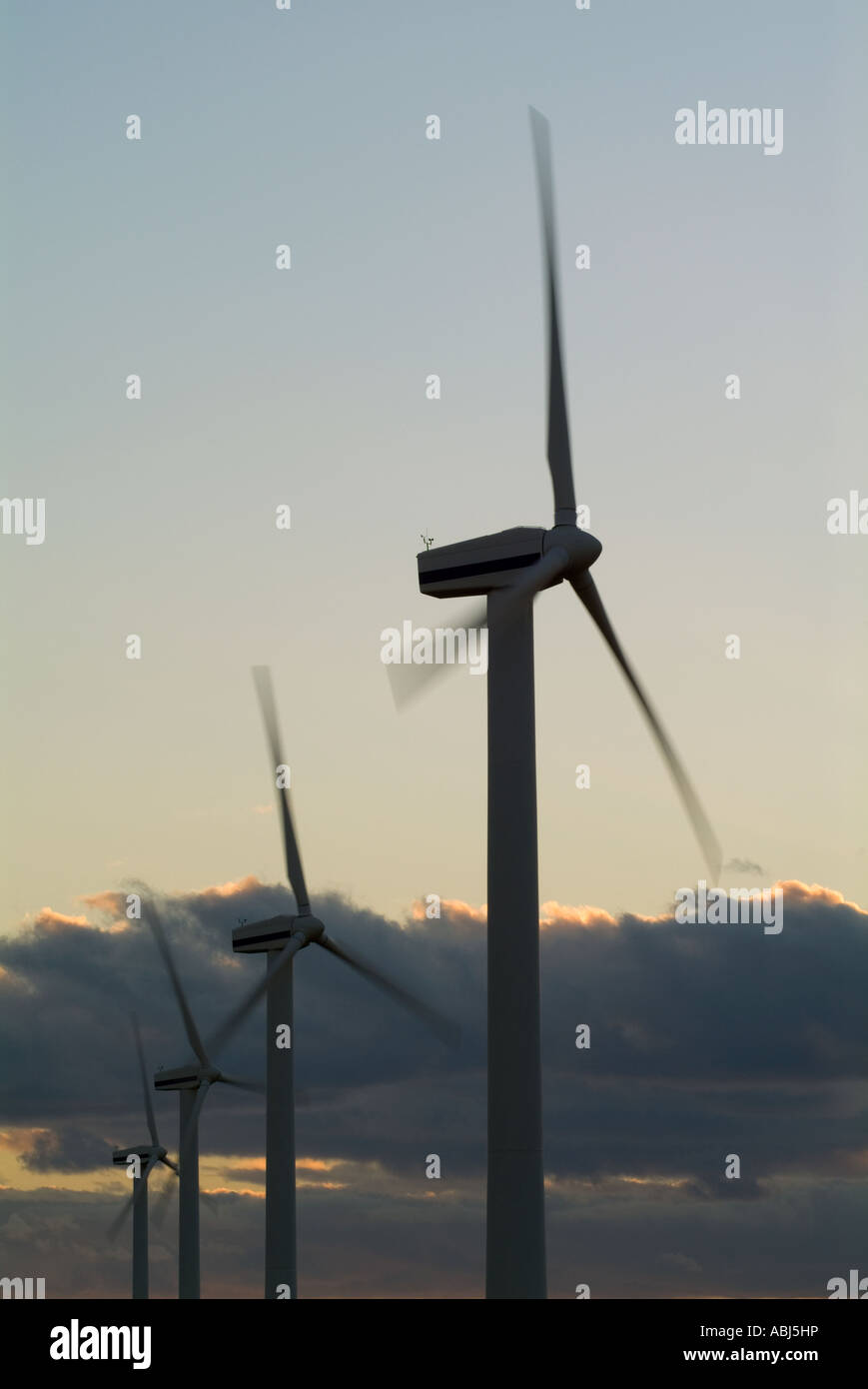 An image concerning energy of silhouetted windmills on an english coast shot at sunset with deep blue skies and some motion blur Stock Photo