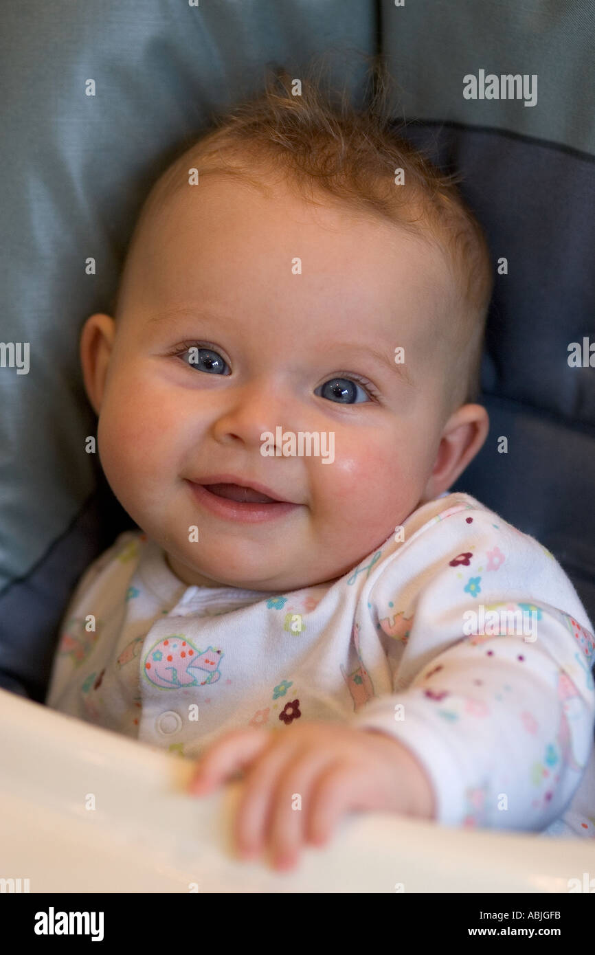 six month old baby girl sitting in her high chair Stock Photo Alamy