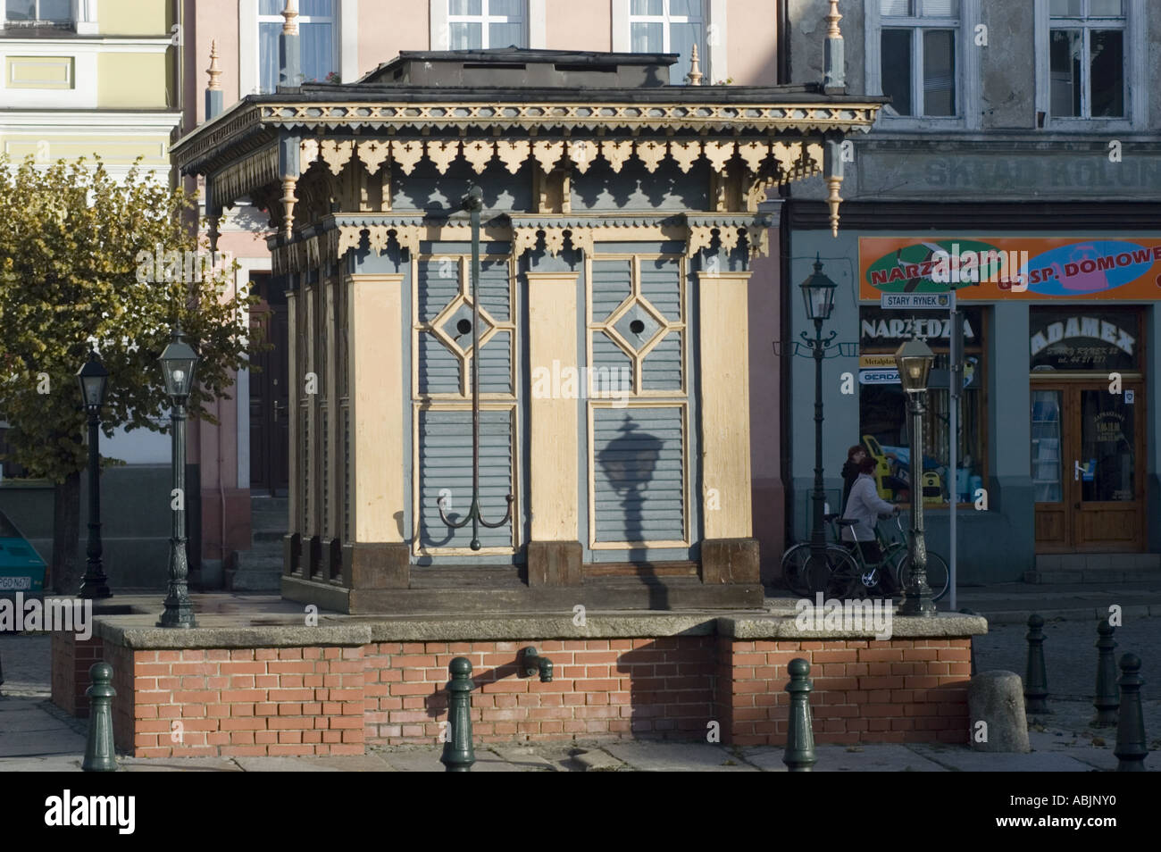 St Bernard heritage pump wheel on Old Market Square in Grodzisk Wlkp, Poland. Ornate historic wooden water pump structure in a town square. Stock Photo