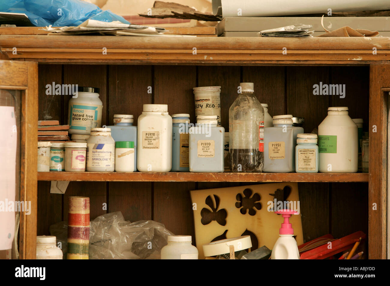 shelf of artistic pottery school bottles of paints paint and chemicals plastic bottles arranged on a shelf messy spotty stains Stock Photo