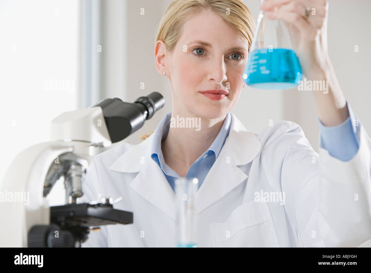 Female scientist looking at liquid in beaker Stock Photo Alamy