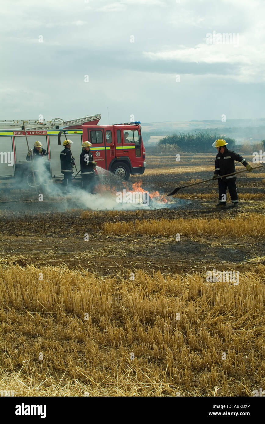 Firefighters extinguishing burning barley field after the baler fire, Yorkshire, UK Stock Photo