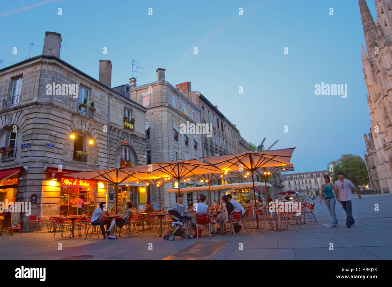 A cafe on the place pey berland in Bordeaux, outside seating terrasse lit  by electric lights, people sitting drinking and walking on the square,  Place Pey Berland. city Bordeaux Gironde Aquitaine France