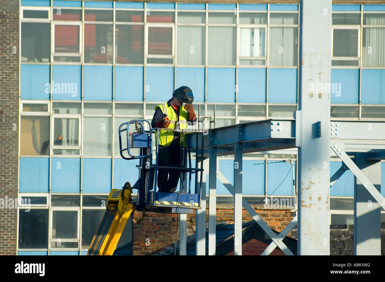 Welder working from a mobile access platform on a construction site in Manchester, England, UK Stock Photo