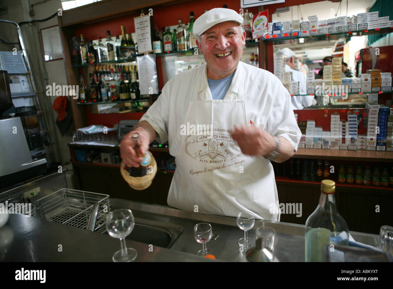 A happy Italian shop keeper offering wine to holiday makers in a