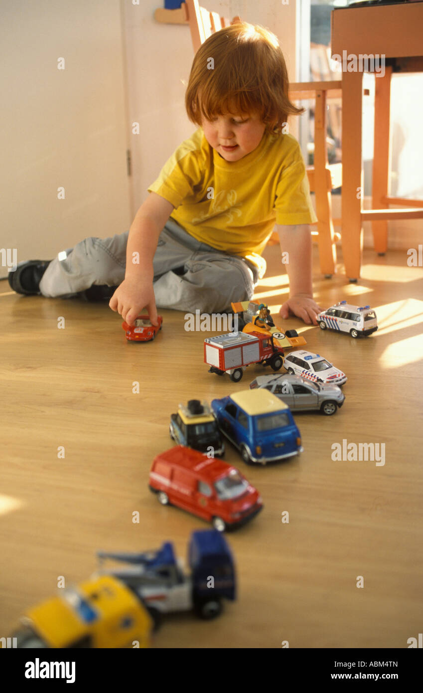 Little boy is playing on the floor with toy cars Stock Photo