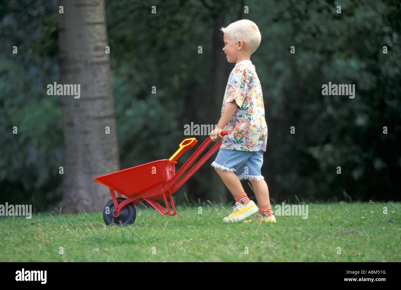 Little boy walking with a wheelbarrow Stock Photo - Alamy