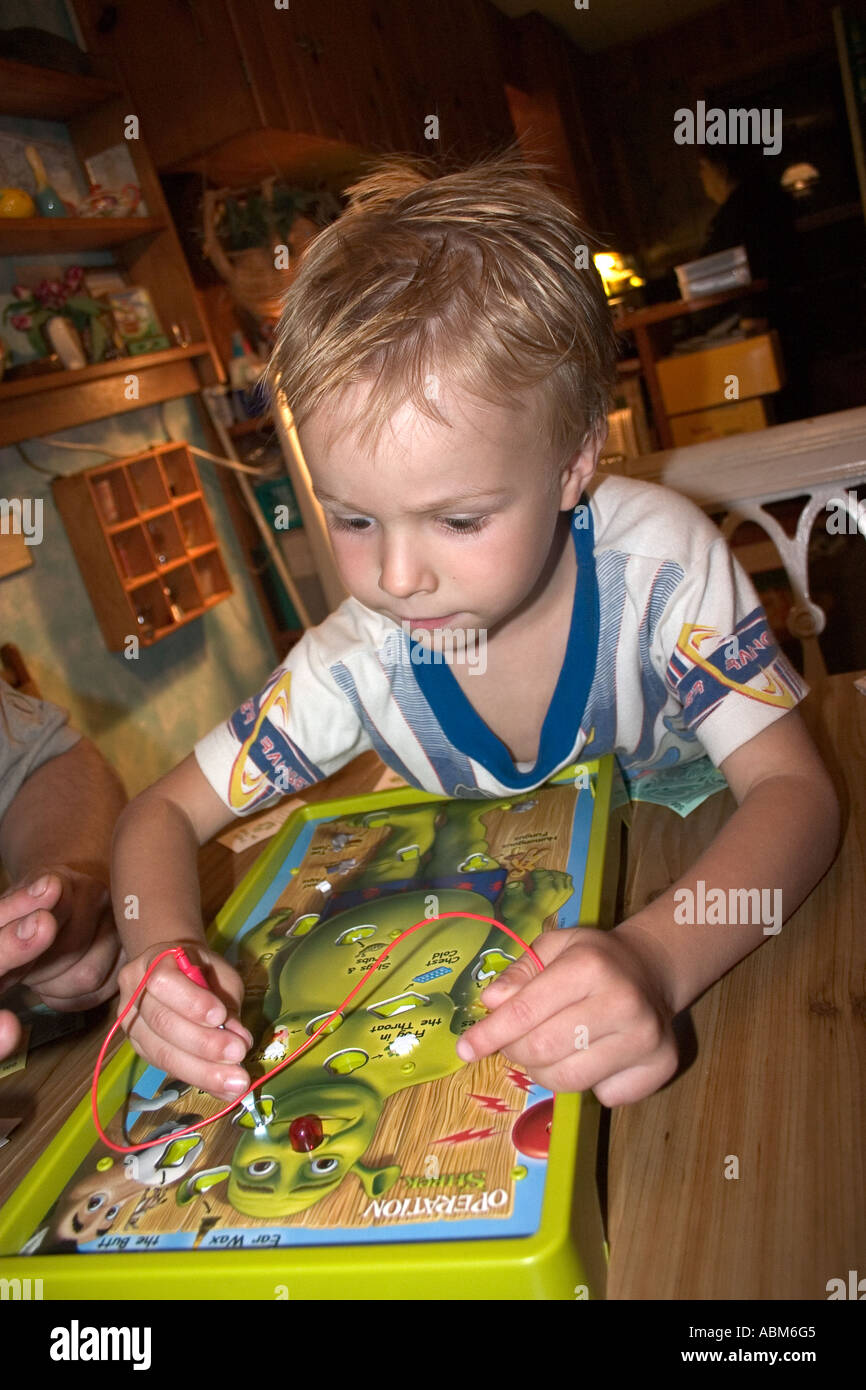 Young boy age 4 intensely involved in the game of Operation Shrek. Clitherall Minnesota MN USA Stock Photo