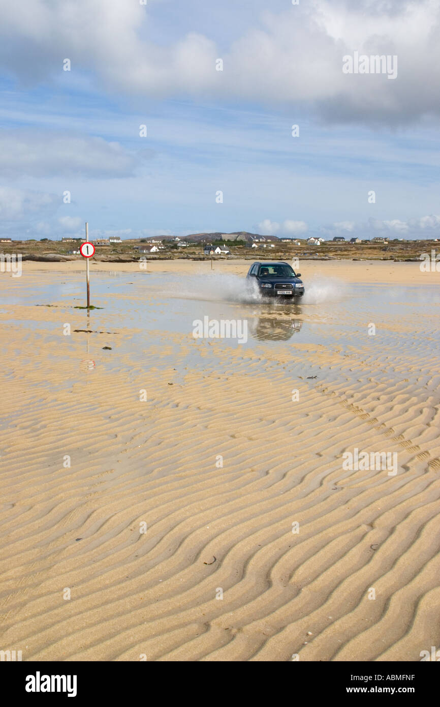 Car crossing the strand at low tide to Omey Island  Connemara  reland Stock Photo