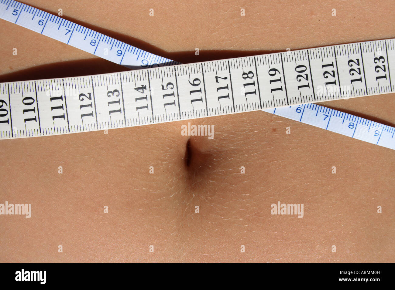 belly of a young woman measuring waist. Measuring tape INCH and CM