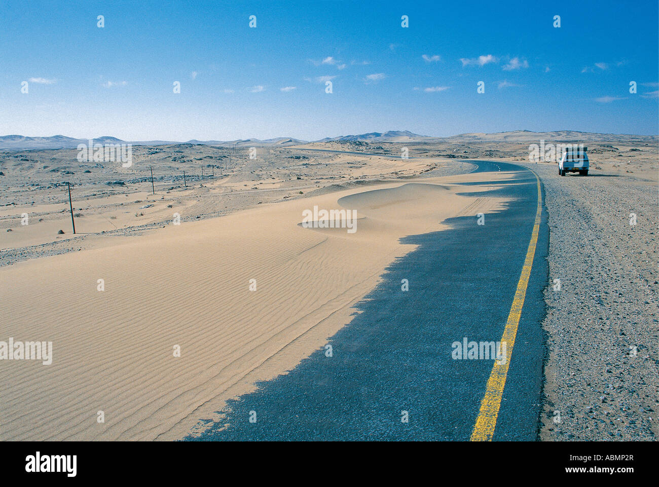 The shifting sands of the Namib Desert frequently cover the tarmac road to Luderitz Namibia Stock Photo