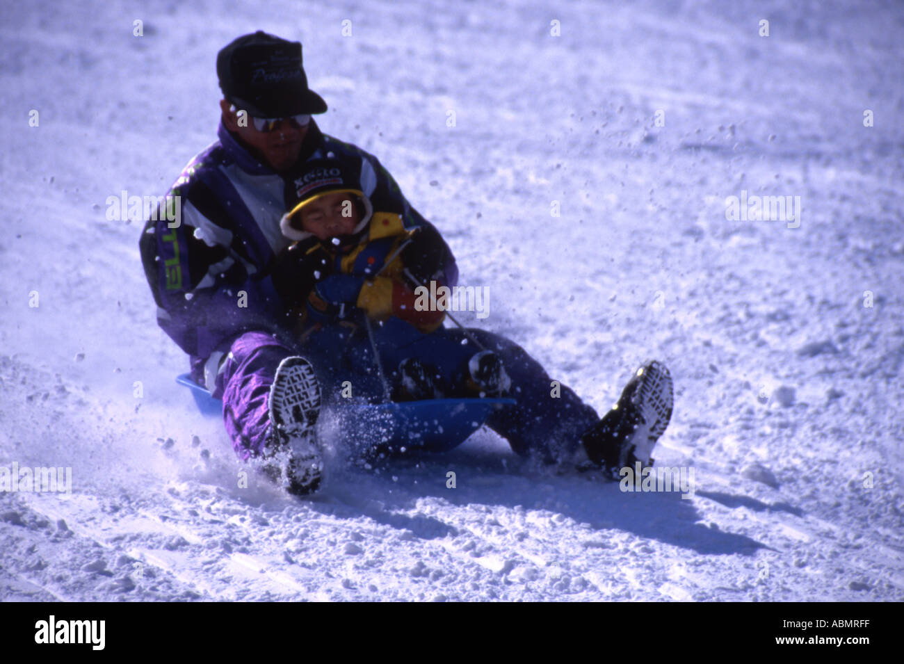 Young boy and his father sled down the snow covered slopes Hokkaido Japan Stock Photo