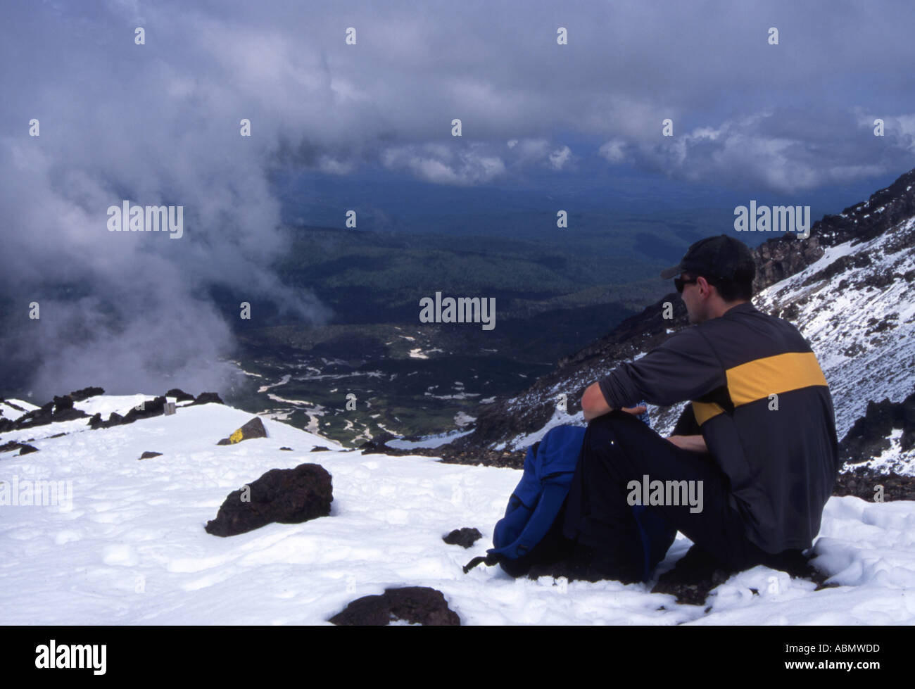 Hiker views the scenery as while he rests on the ascent of Asahi Dake the highest mountain in Hokkaido Japan Stock Photo