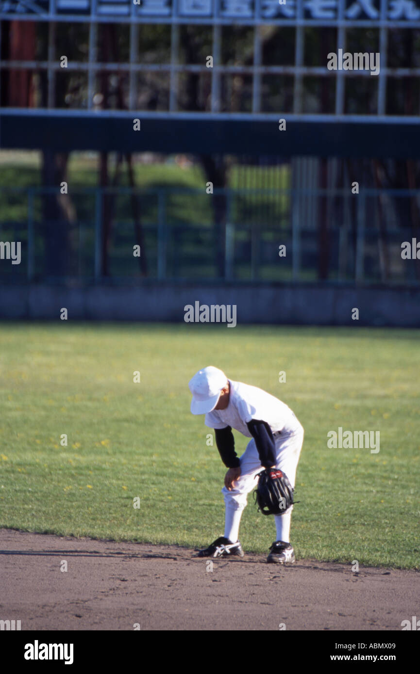 Japanese little league baseball player stands in the outfield waiting for a catch Stock Photo