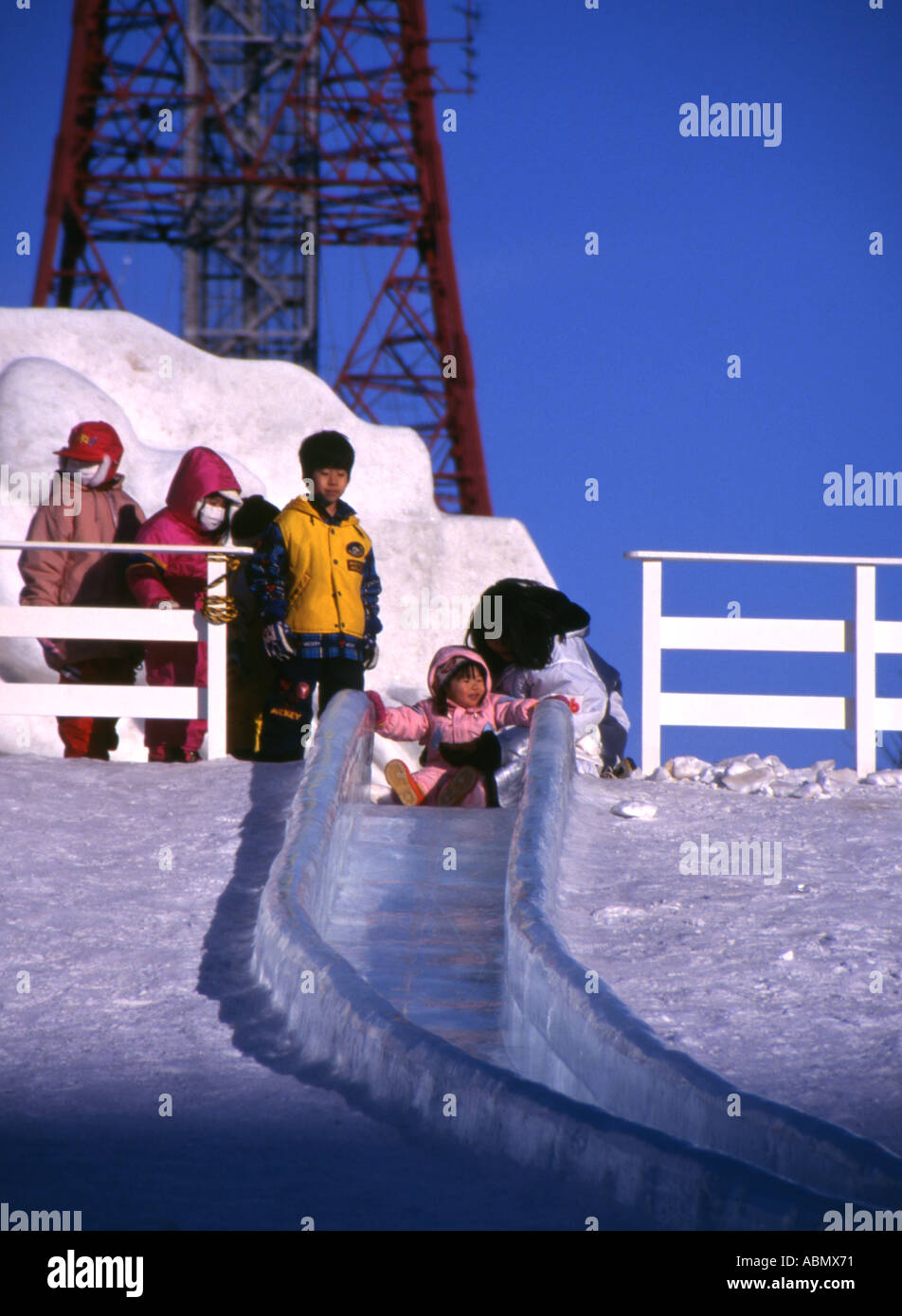 Little Japanese girl about to slide down ice slide at Sapporo Snow Festival Hokkaido Japan Stock Photo