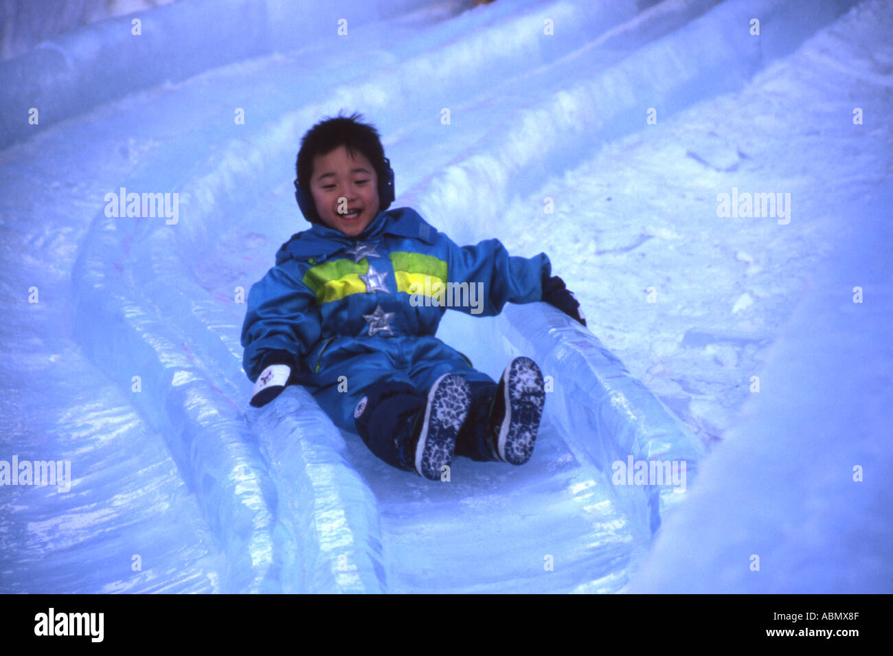 Young boy flies down ice slide at Sapporo Snow Festival Hokkaido Japan Stock Photo