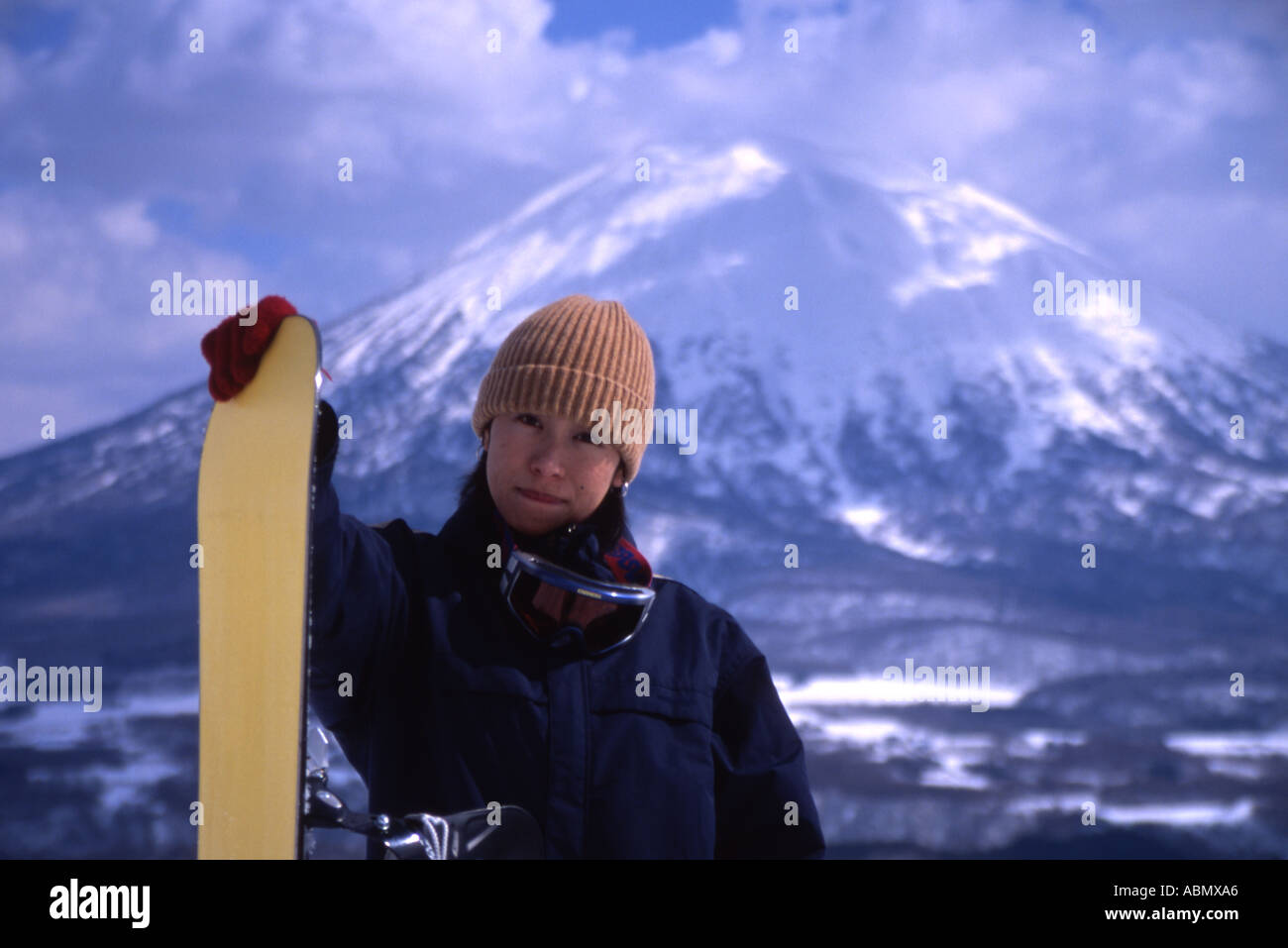 Japanese snowboarder girl woman with Mt Yotei behind her Niseko Hokkaido Japan Stock Photo