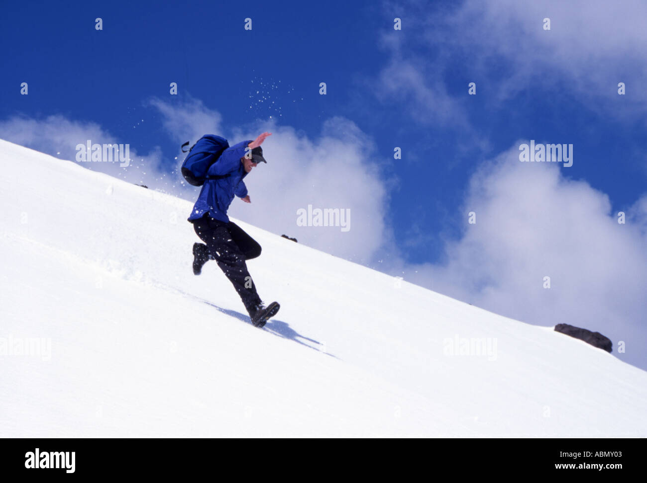 Hiker runs and jumps down the snow covered slopes of Mt Asahi Asahi dake in Hokkaido Daisetsuzan National Park Japan Stock Photo