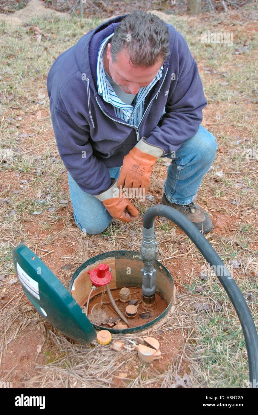 Propane delivery man putting pumping natural gas into underground tank