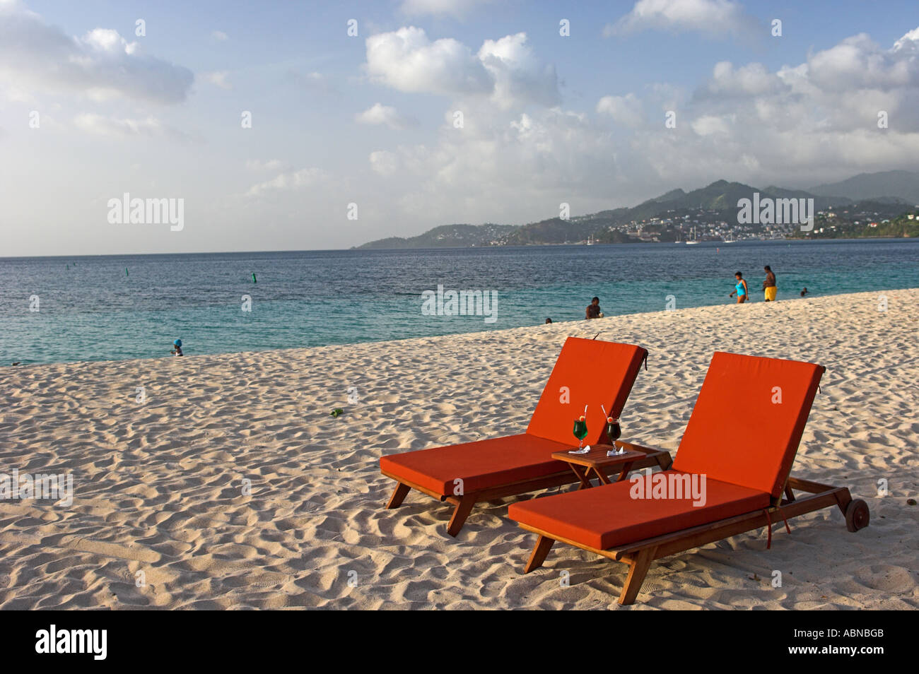 Two empty chars with drinks on golden sand beach late afternoon Grand Anse Beach Grenada Caribbean Stock Photo