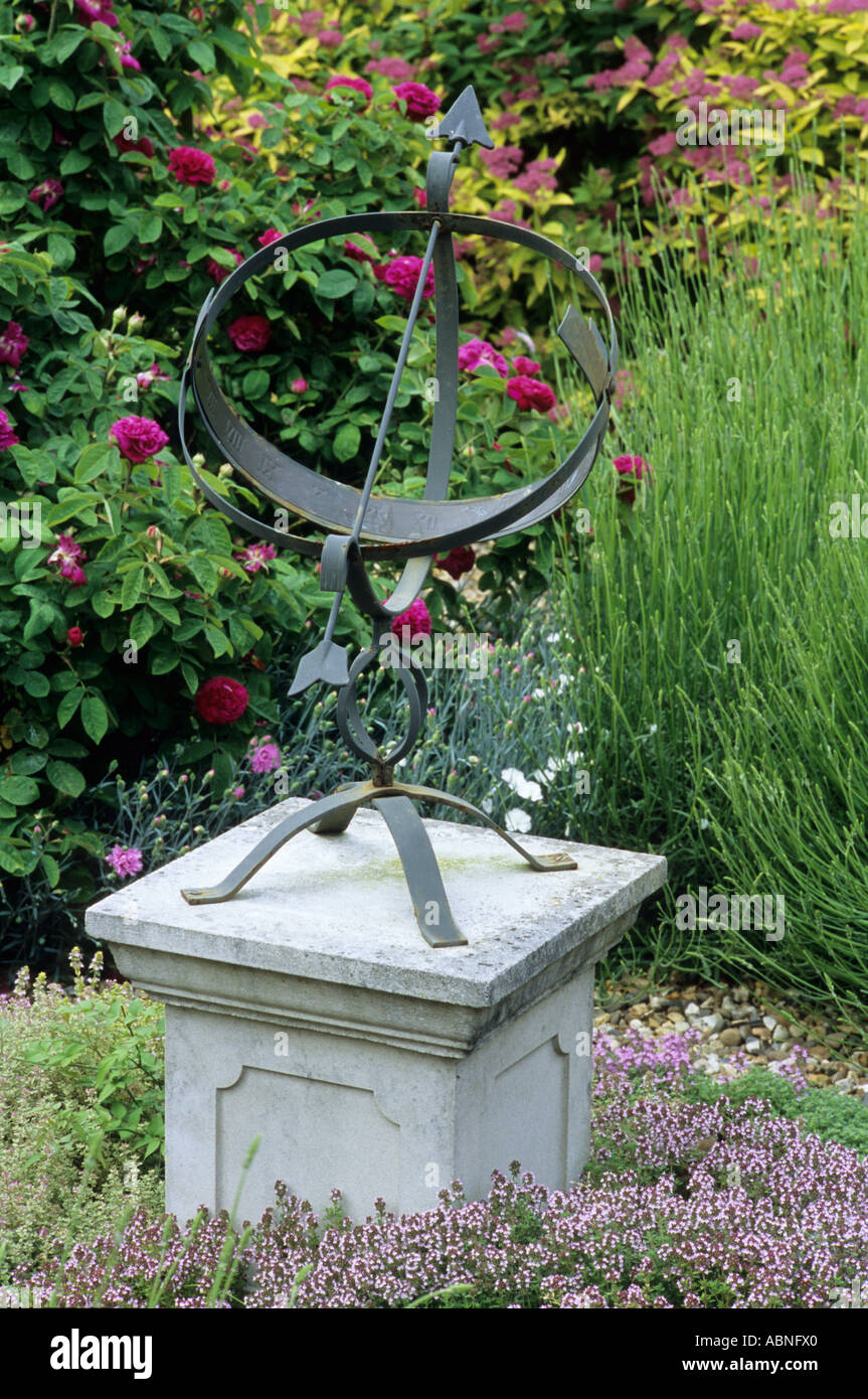 Sundial in garden on stone plinth with thymus and roses hires stock