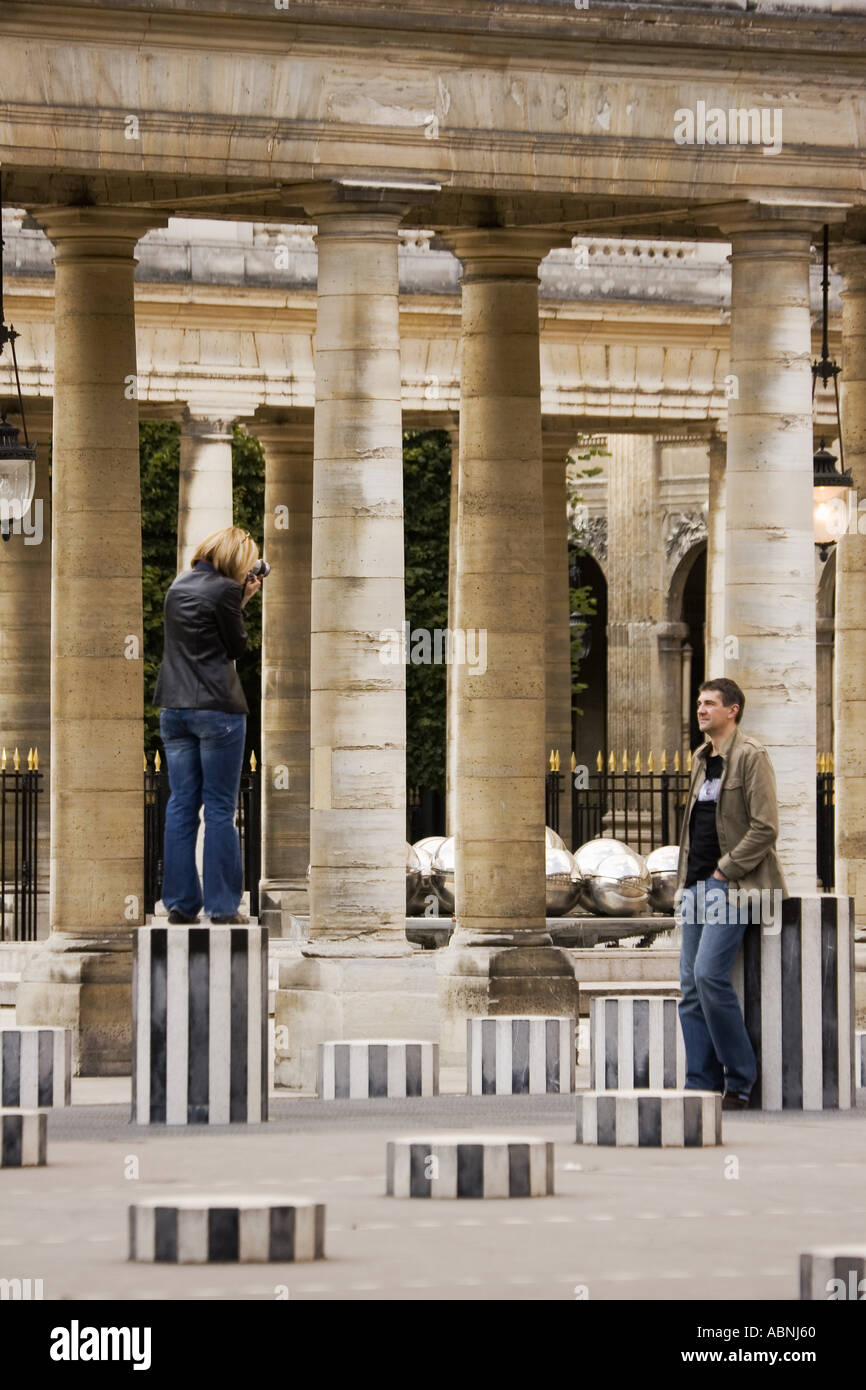 Woman taking picture of man among sculpture columns at Palais Royal Paris France Stock Photo