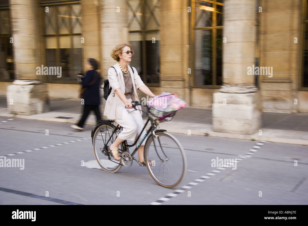 Woman riding bicycle through courtyard of the Palais Royal Paris France Stock Photo