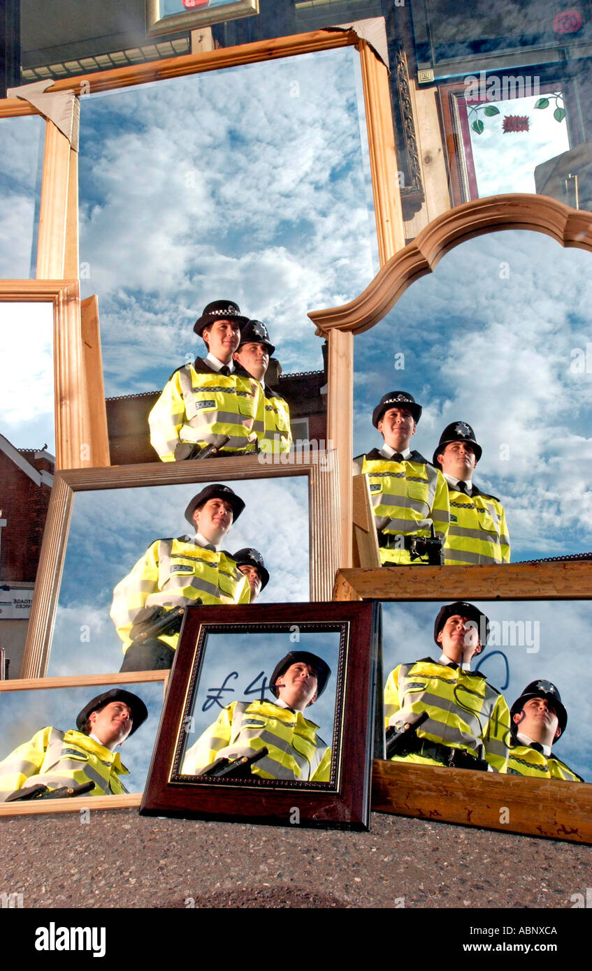 Two police officers, a man and a woman,  reflected in mirrors in shop window in Sussex Stock Photo