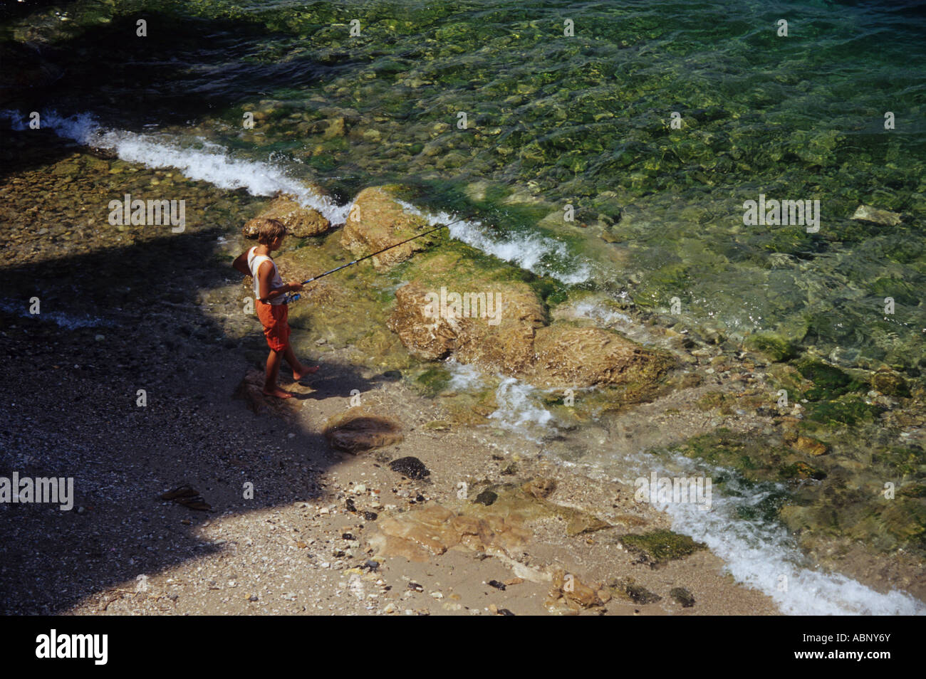 Boy Fishing in the Castle Shadow at Malcesine Lake Garda Italy Stock Photo