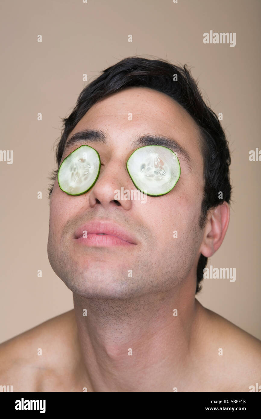 Man wearing cucumbers over eyelids Stock Photo Alamy